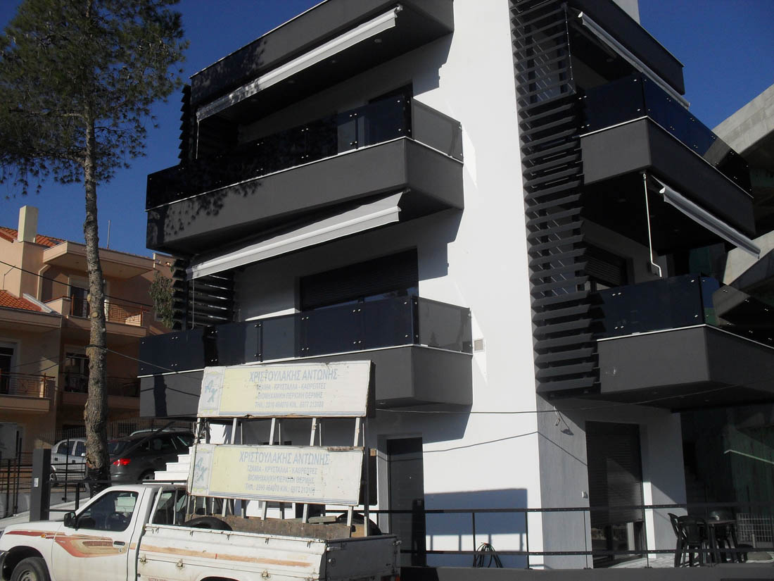 Εξωτερικό 2όροφης πολυκατοικίας με μαύρα μπαλκόνια από γυάλινα κάγκελα μετωπικής στήριξης